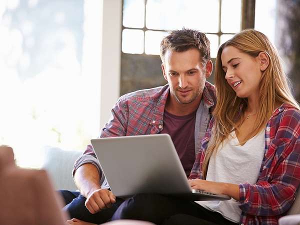 young couple wearing flannel on computer