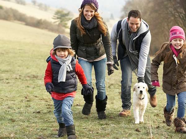 young family walking up fall hill with dog